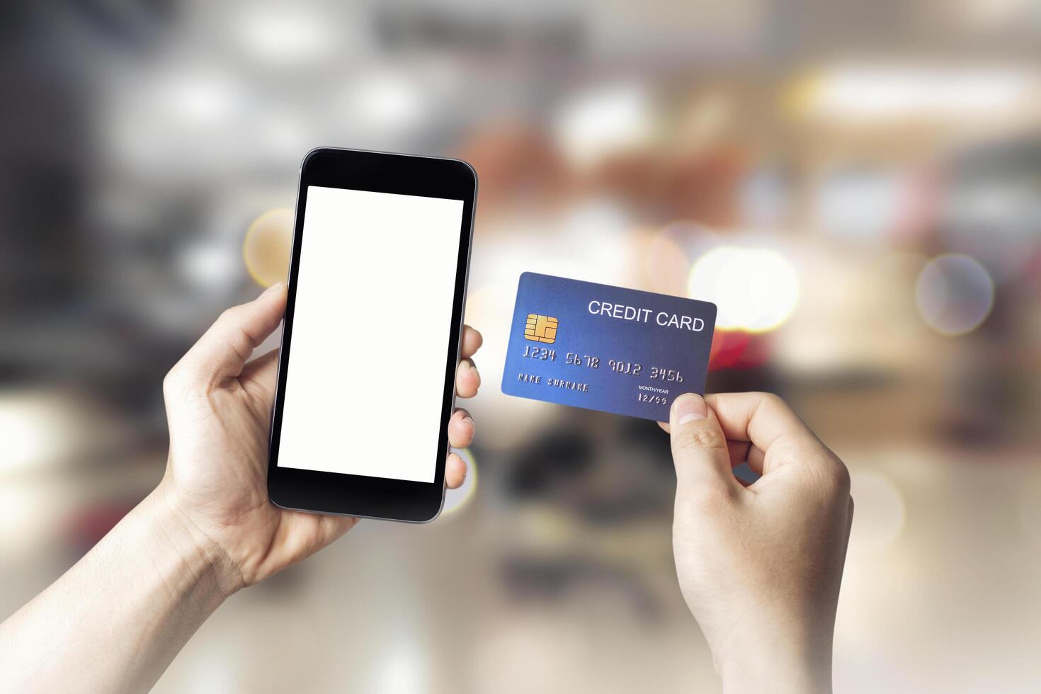 Hands holding credit card with Smart mobile phone show white screen background for your design online shopping on shopping mall background, E-payment technology, Concept of internet banking.copy space photo