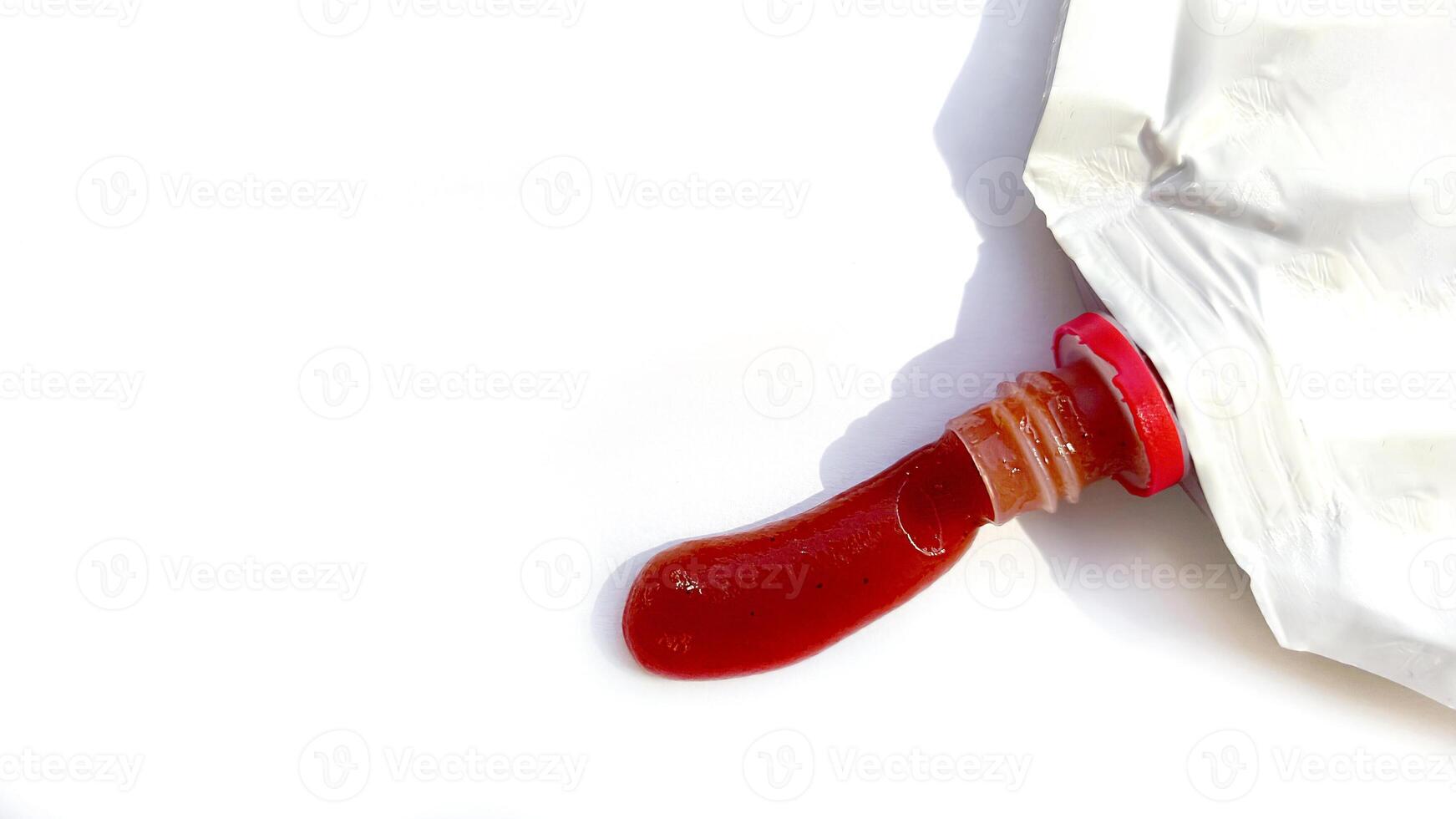 Wet smear of red tomato ketchup with ketchup packaging isolated on white background with copy space photo