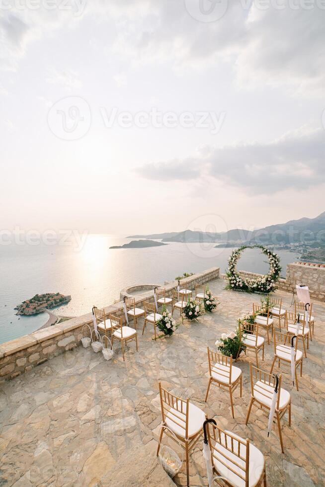 Rows of chairs stand in front of a round wedding arch on the observation deck above the island of Sveti Stefan. Montenegro photo