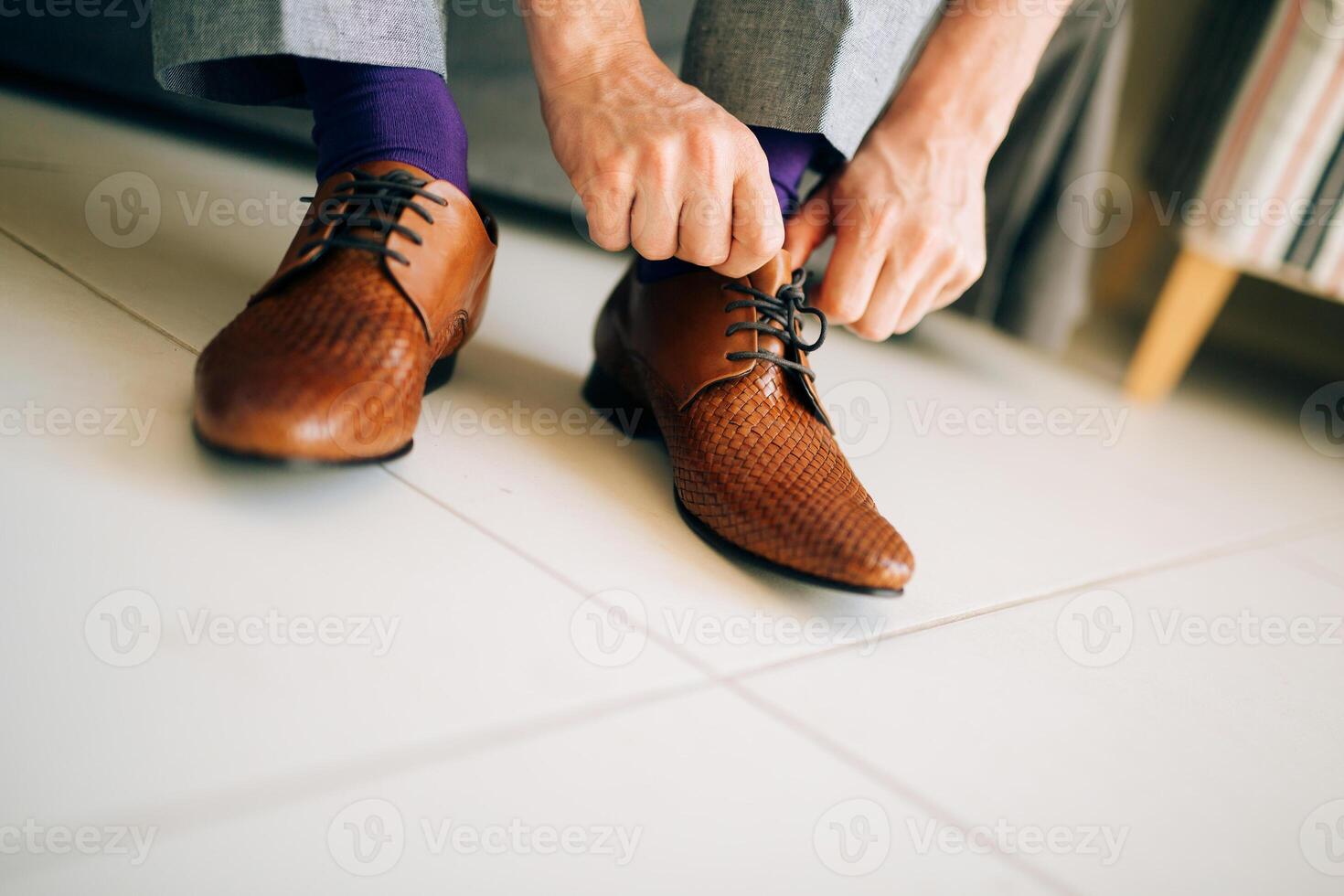 A man is tying his brown dress shoes while wearing colorful socks photo