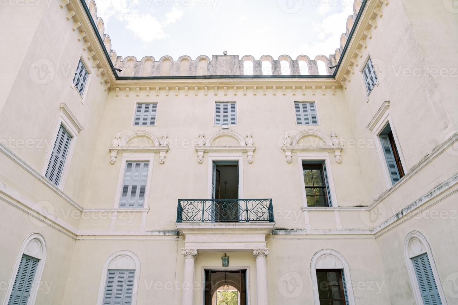 Internal corner facade of an ancient villa with a wrought-iron balcony and stucco molding photo
