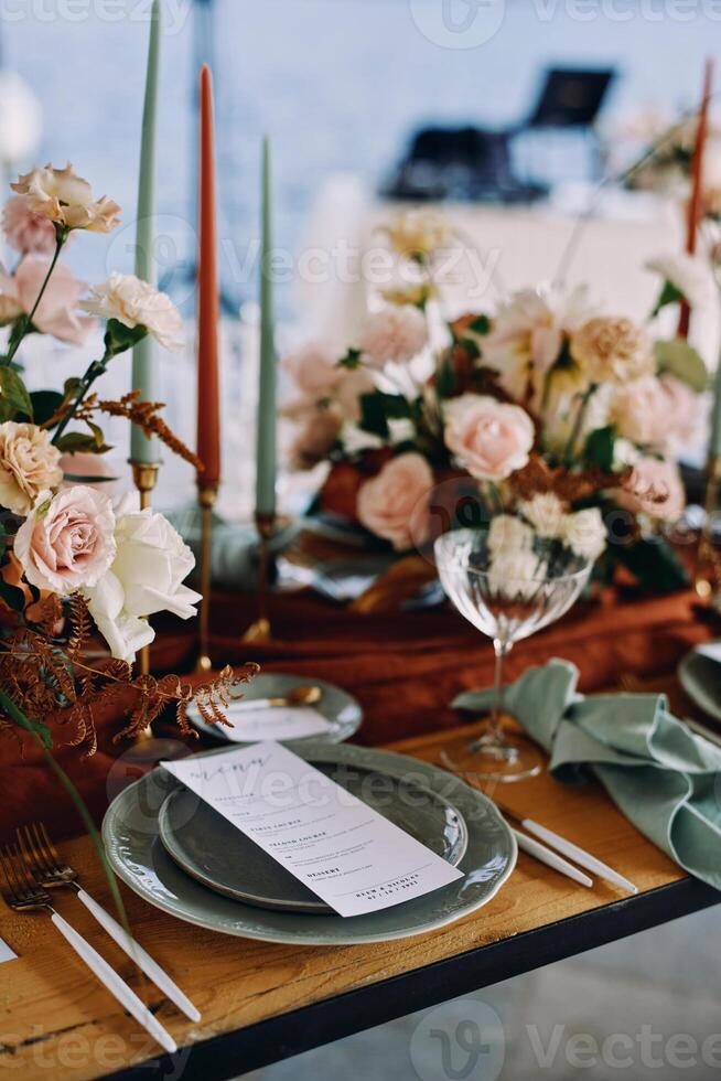 Festive menu lies on a plate next to a bouquet of flowers on a set table photo