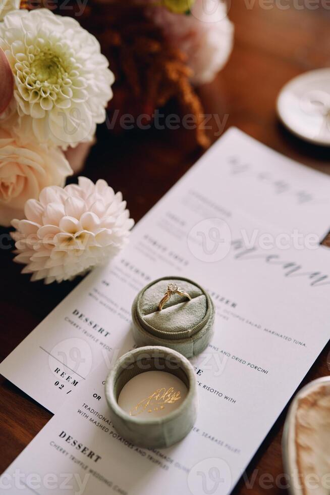 Engagement ring in a box lies on a holiday menu near flowers photo