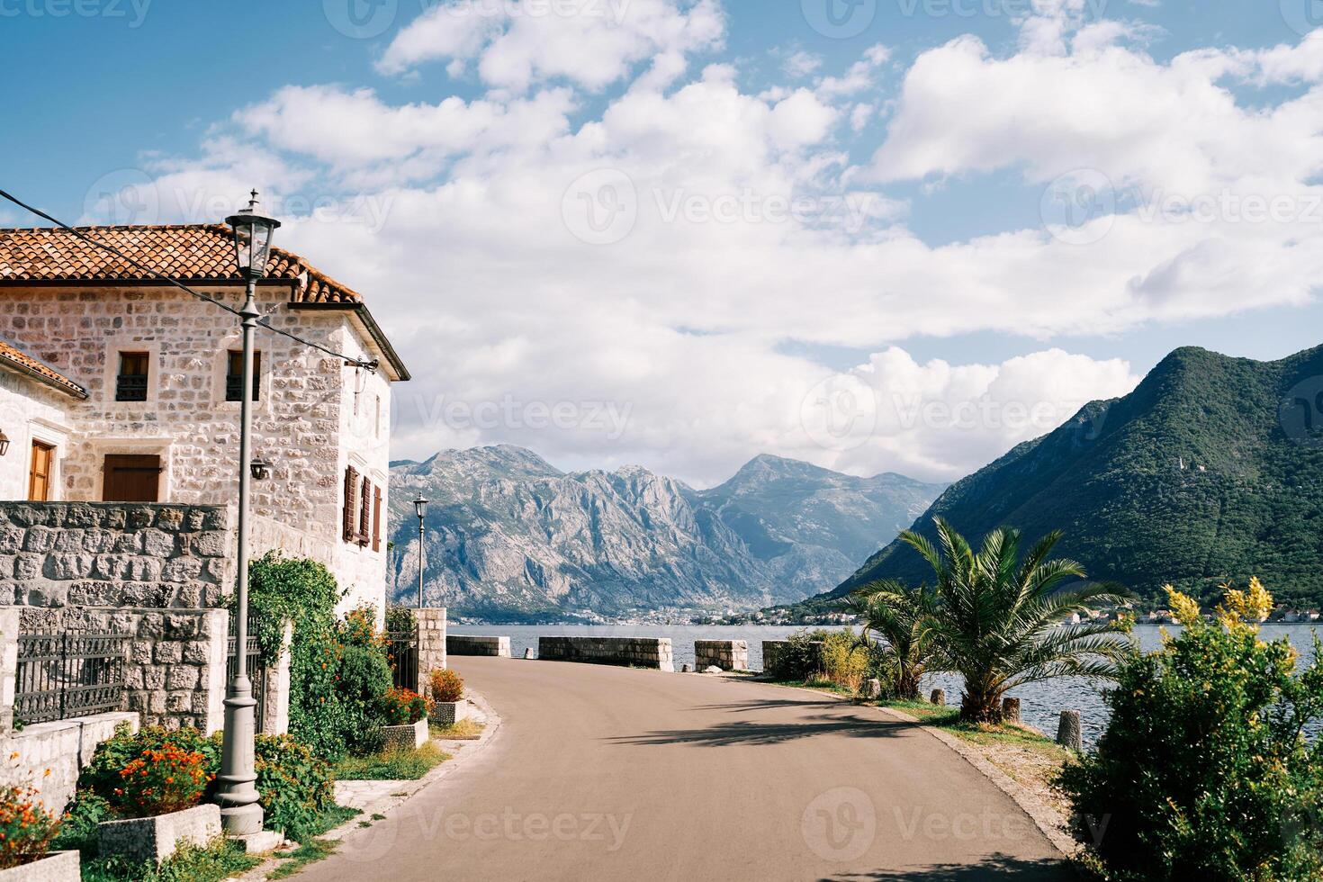Old stone mansion with a green garden at the turn of the road above the sea. Perast, Montenegro photo