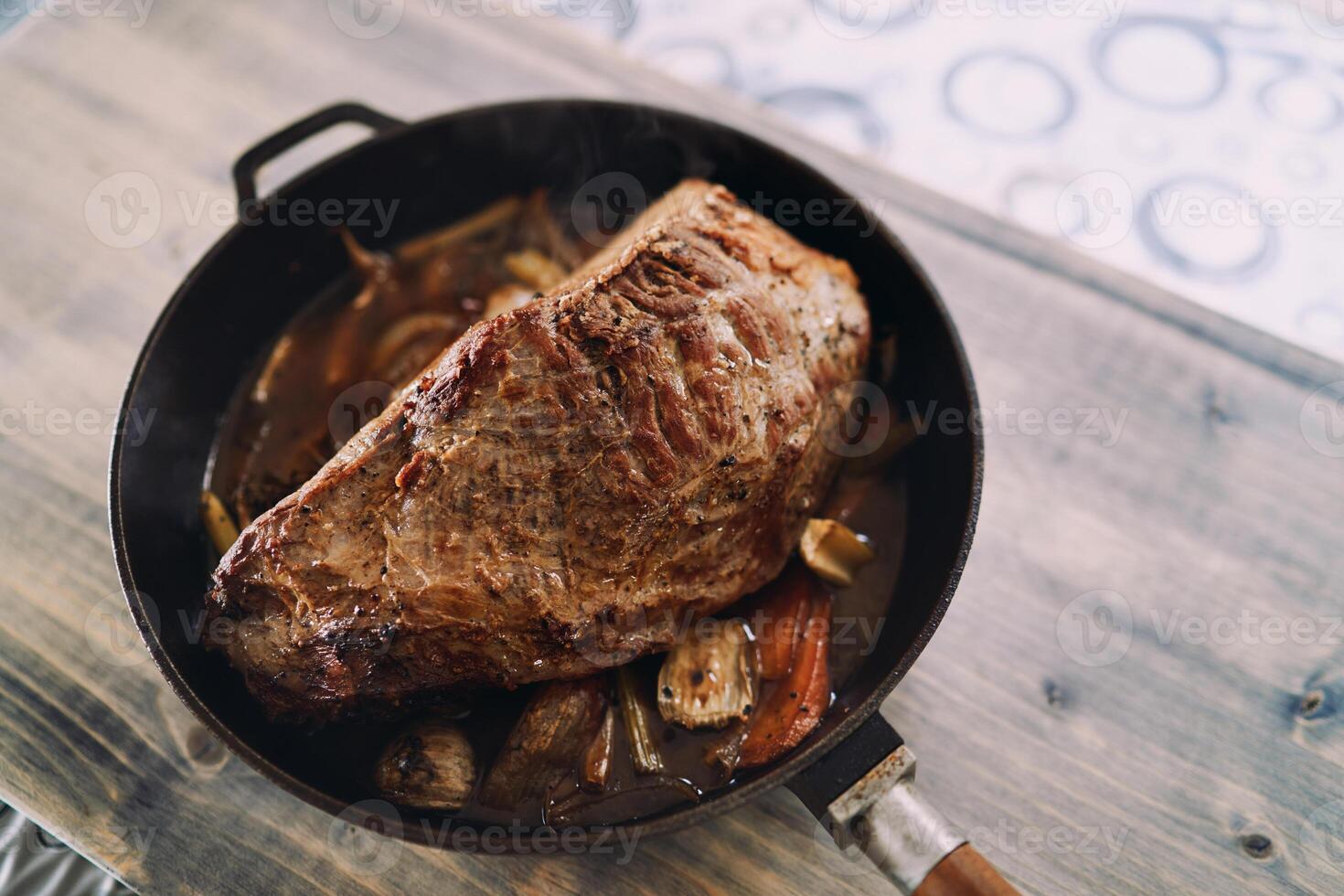 Roast beef with vegetables stands in a pan on a wooden table. Top view photo