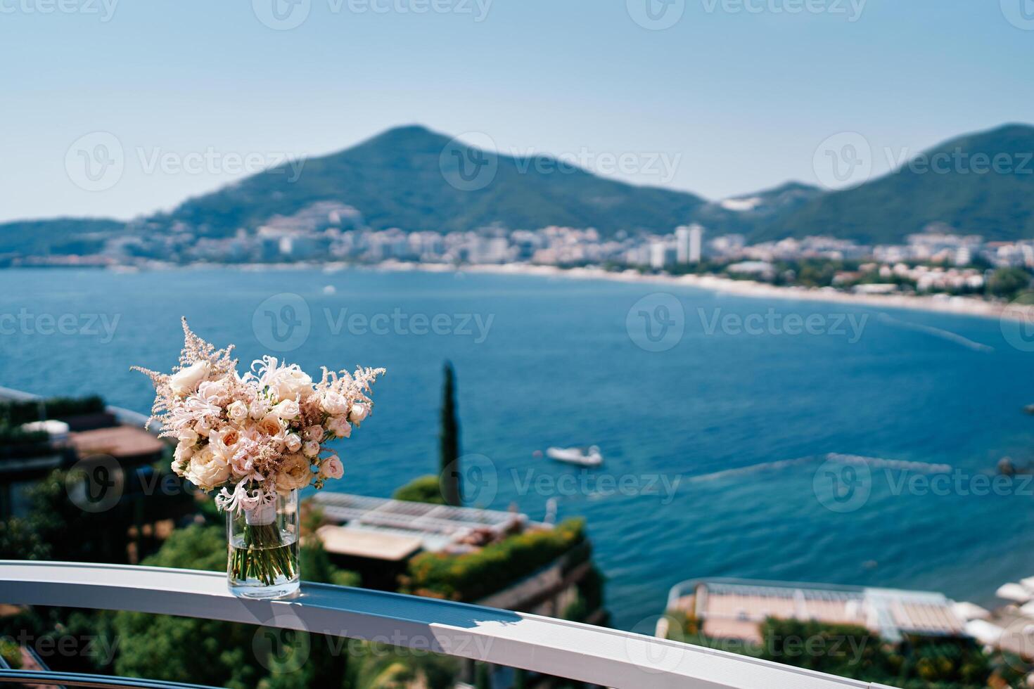 Bride bouquet stands in a vase with water on the railing of the terrace above the sea photo