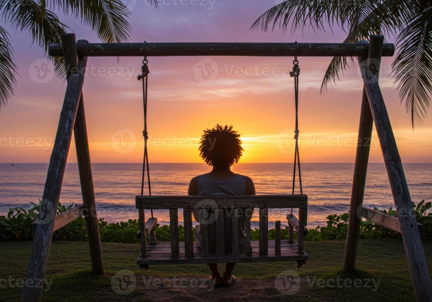 Person Relaxing on Swing at Beach During Sunset with Palm Trees photo
