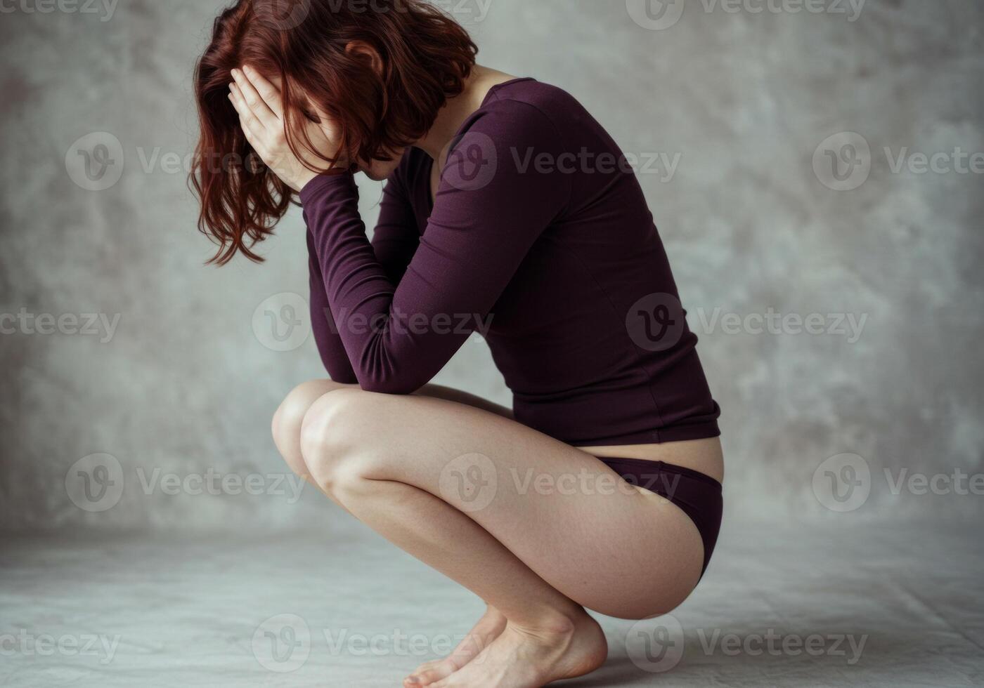 Woman Crouching with Head in Hands Expressing Sadness and Emotional Distress photo