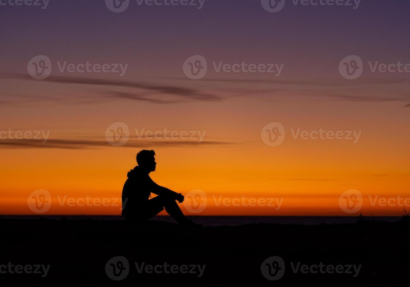 Man Sitting in Silhouette Enjoying a Colorful Dramatic Sunset photo