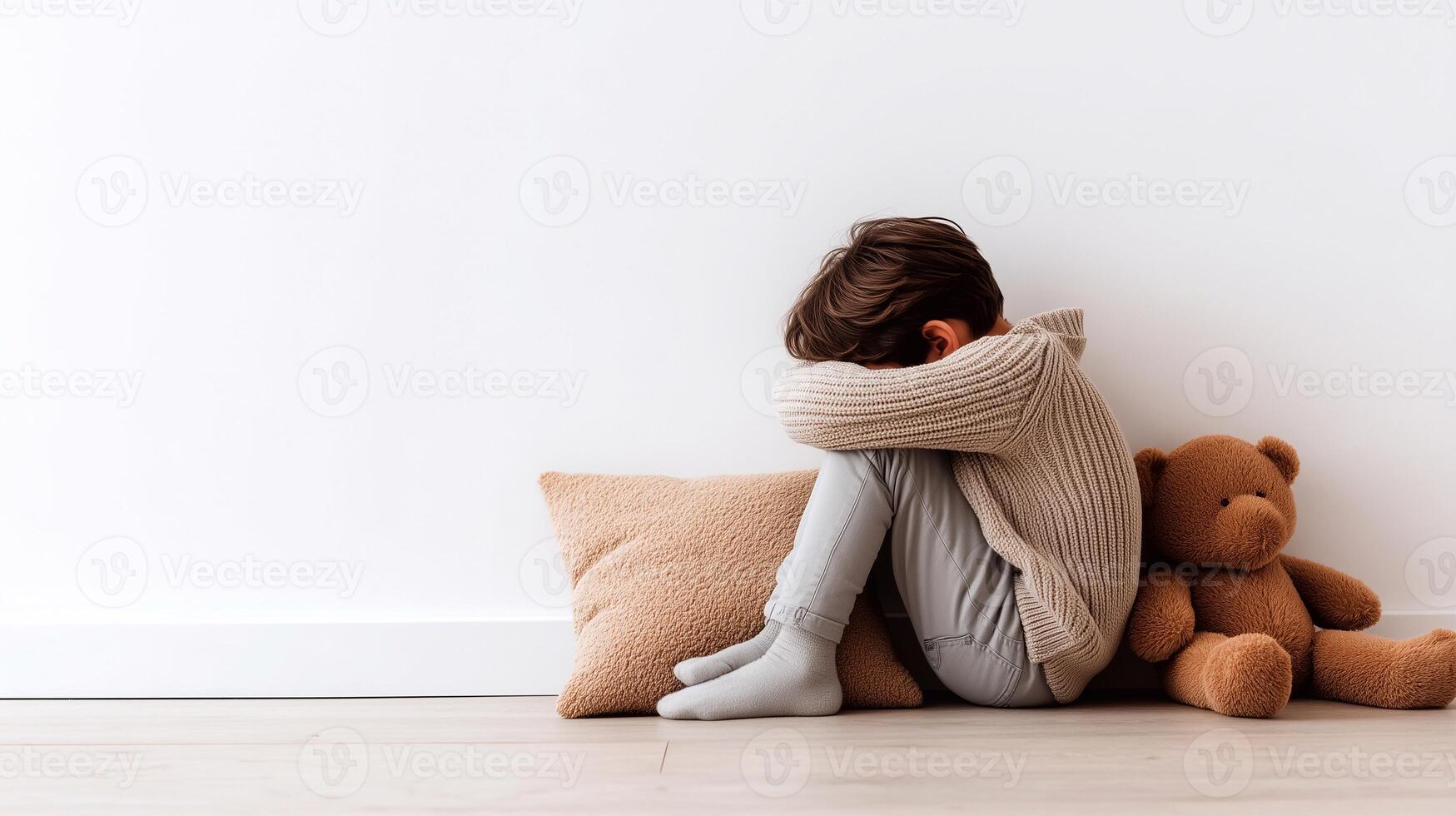A toddler sits curled up in silence, showing signs of emotional overwhelm, age-related crisis, and sensory overload. Concept of mindful, gentle parenting without yelling. photo