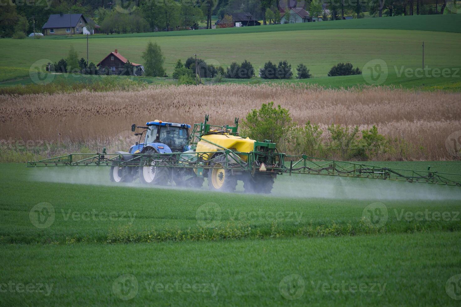 Tractor Spraying Field in Rural Landscape with Lush Green Vegetation photo