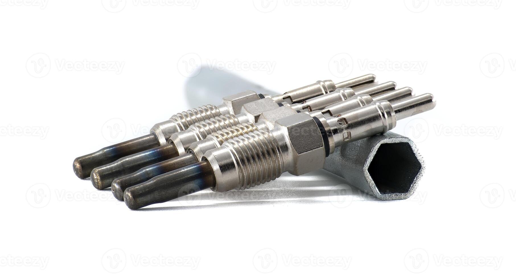 A set of four glow plugs next to a wrench, all against a clean, white background. photo