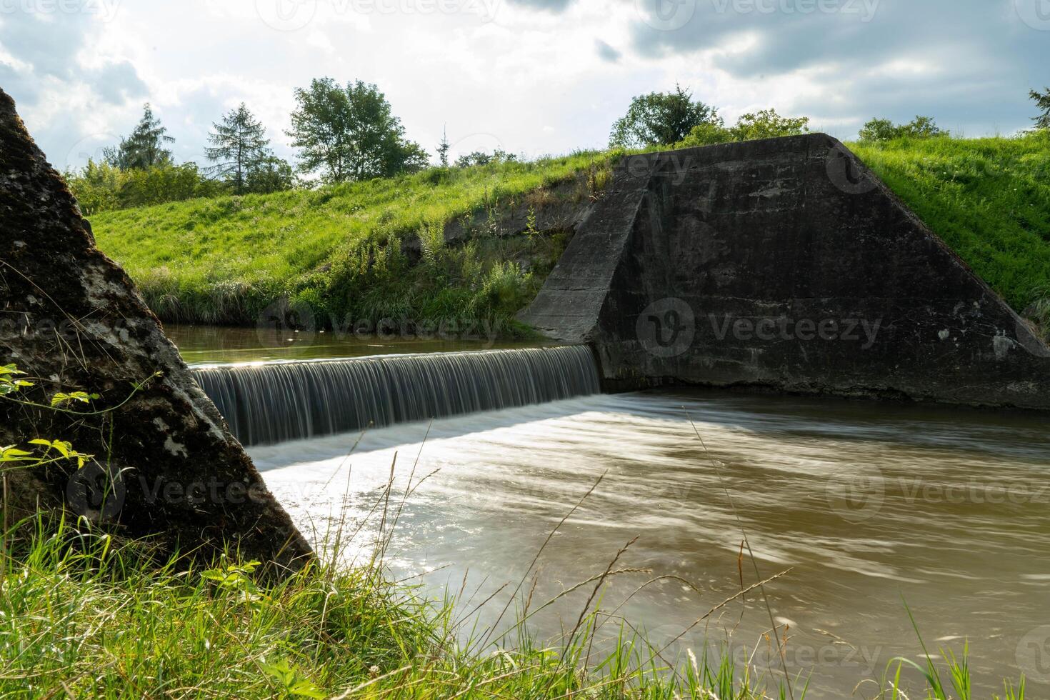Concrete Spillway Flowing through a Lush Green Landscape photo