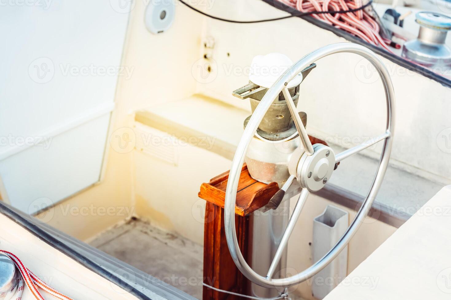 Sailboat steering wheel and deck with ropes in sunlight, suitable as a background photo