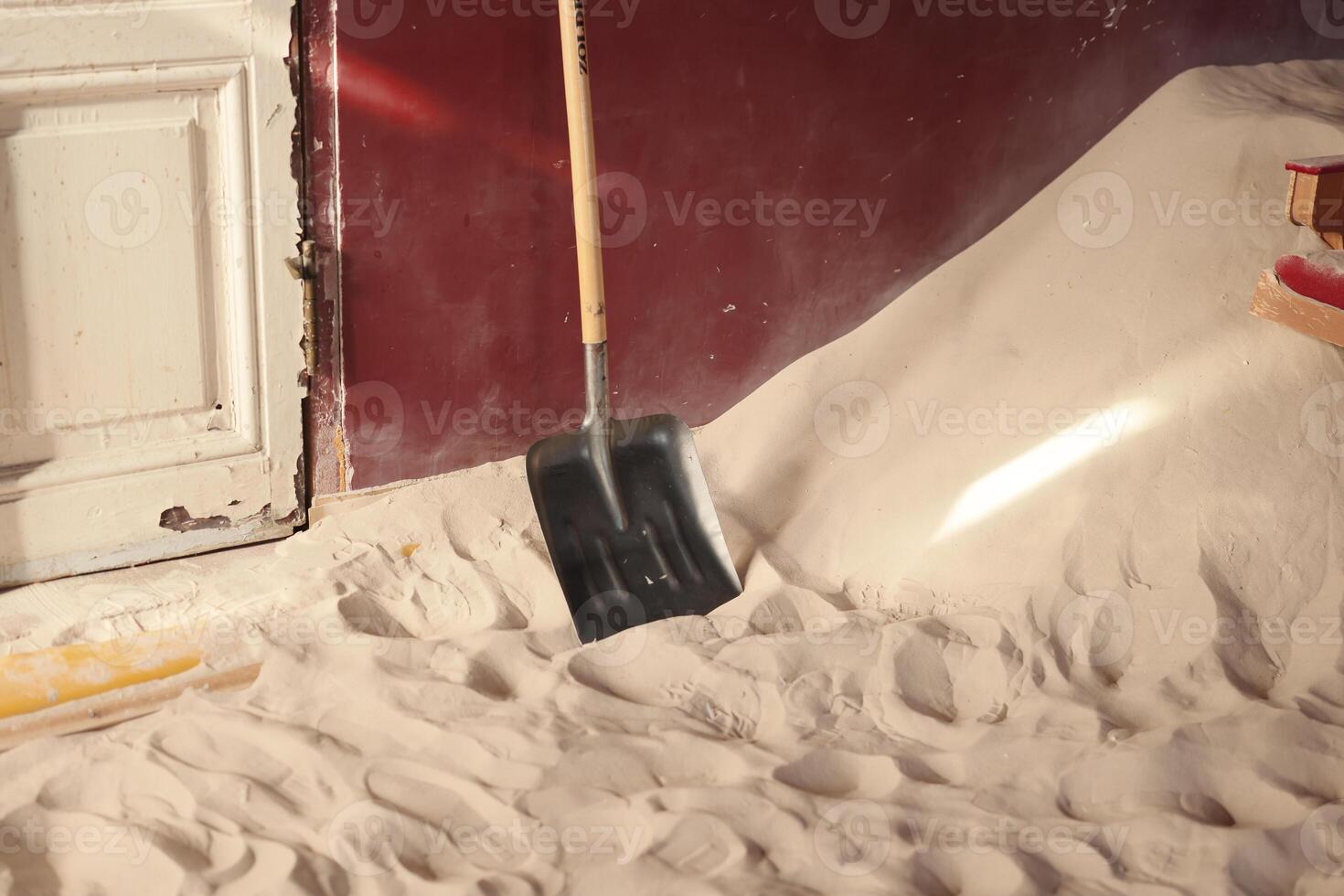 A Shovel is Resting on a Soft Sandy Floor located within an Indoor Environment Space photo