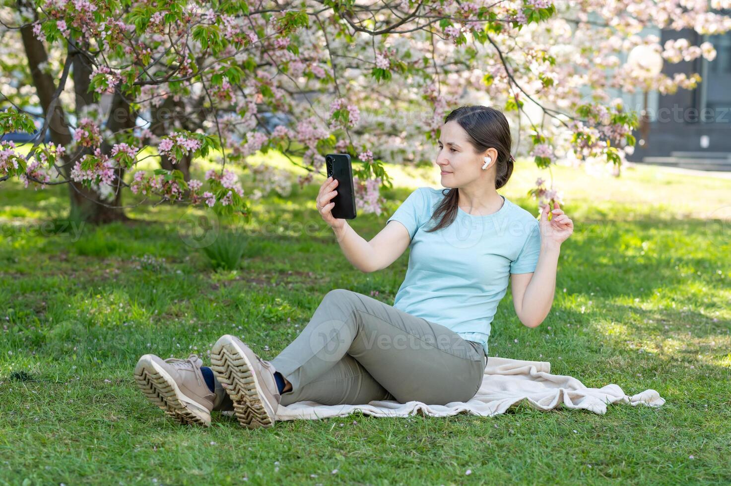 A woman sitting on the grass with her phone photo