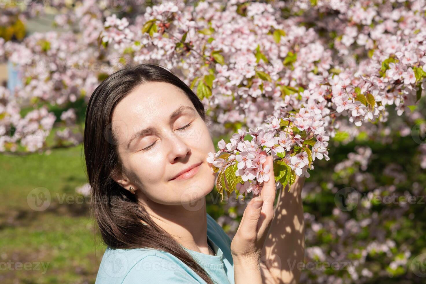 A woman is smelling the blossoms of a tree photo