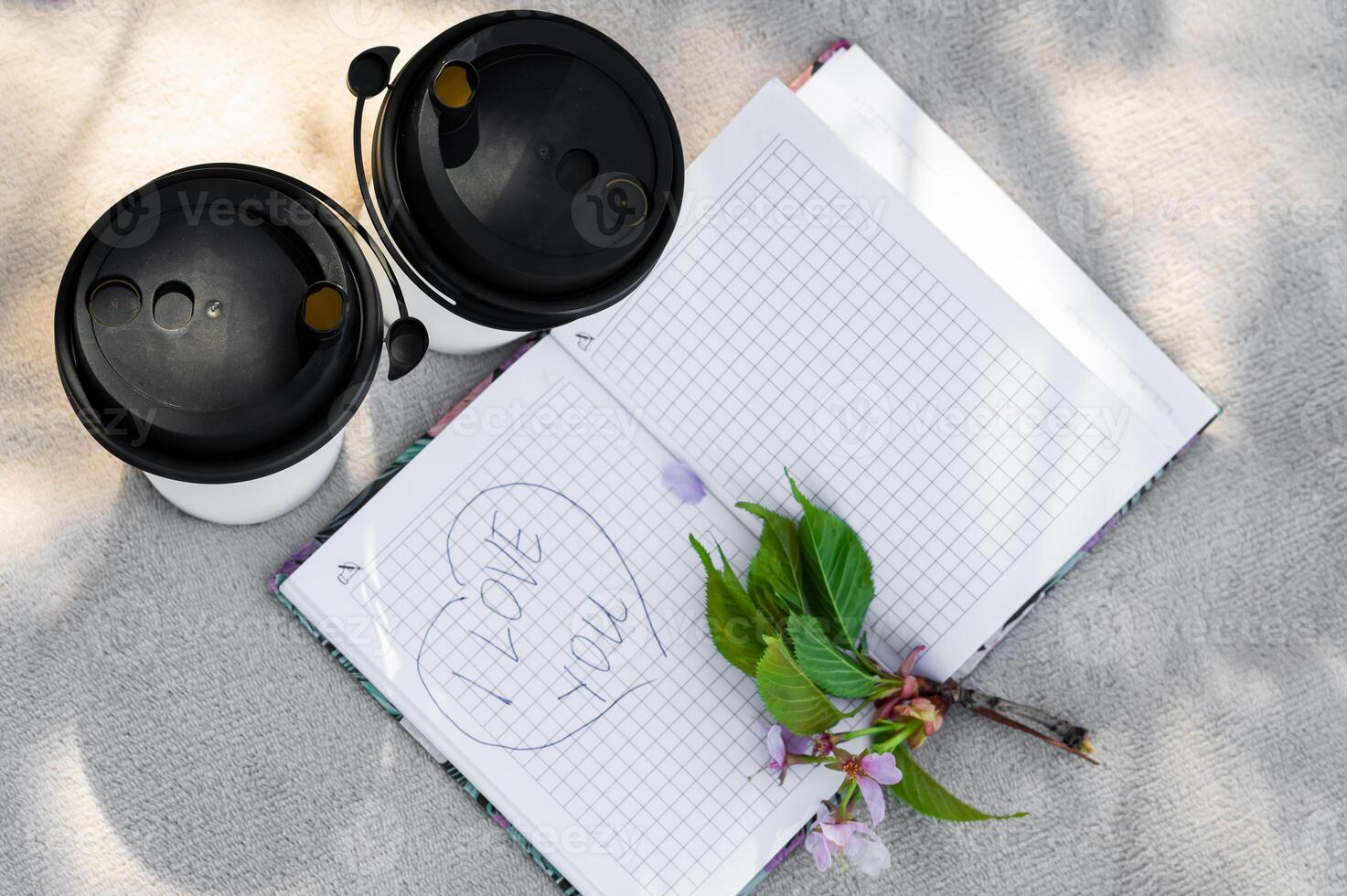A notebook with a flower and two coffee cups photo