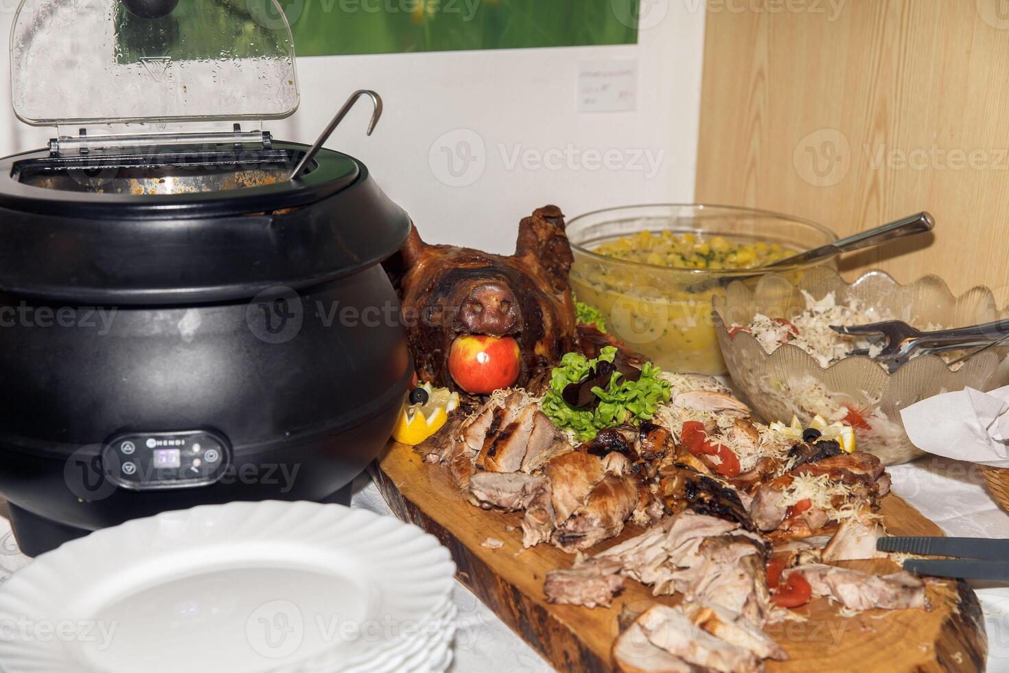 Delicious roast pig feast with vegetables and apple centerpiece on wooden platter photo