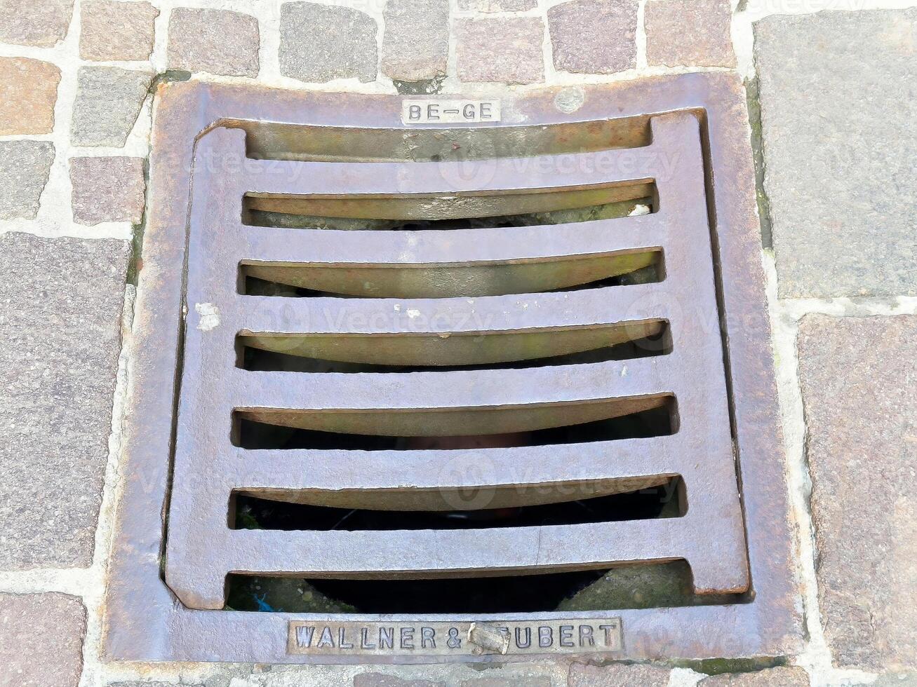 Metal grate on cobblestone street with iron bars and drainage photo