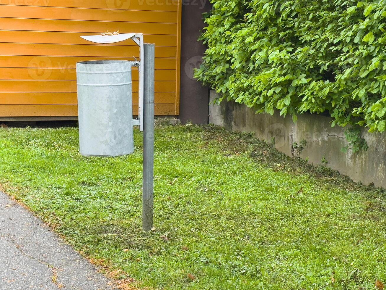 Empty outdoor trash can with canopy lid in urban park setting photo