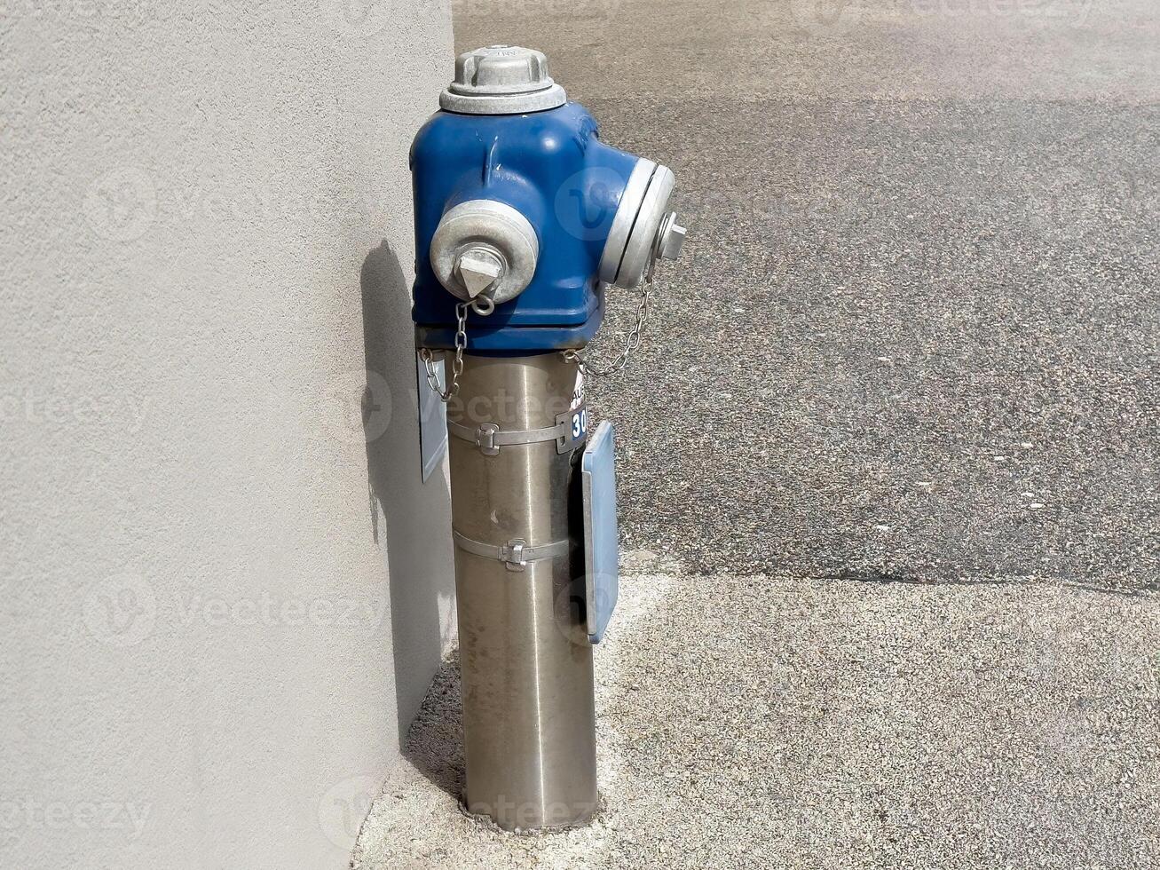 Blue fire hydrant attached to a wall in urban setting photo