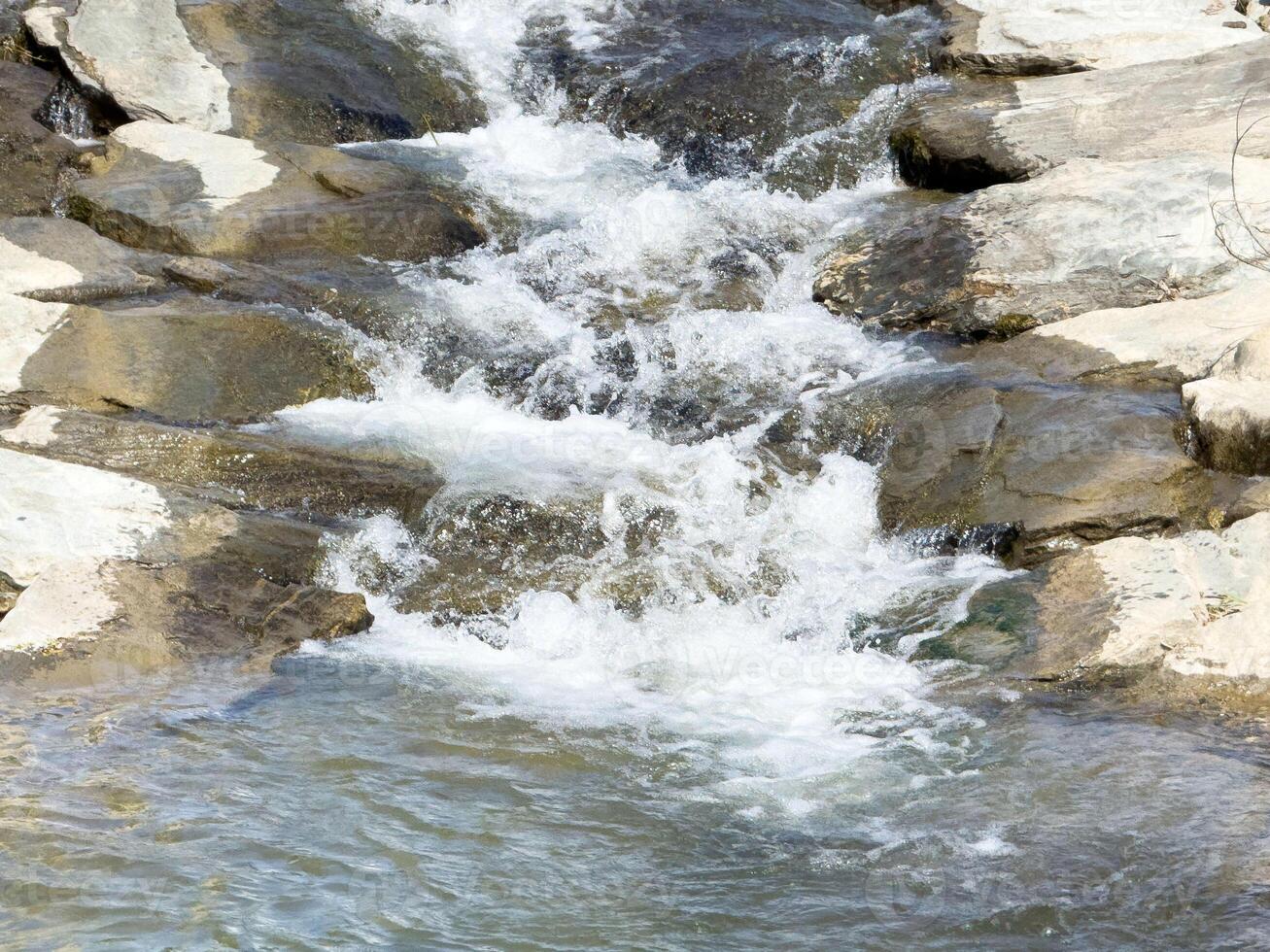 Serene mountain stream cascading over rocks in natural landscape photo