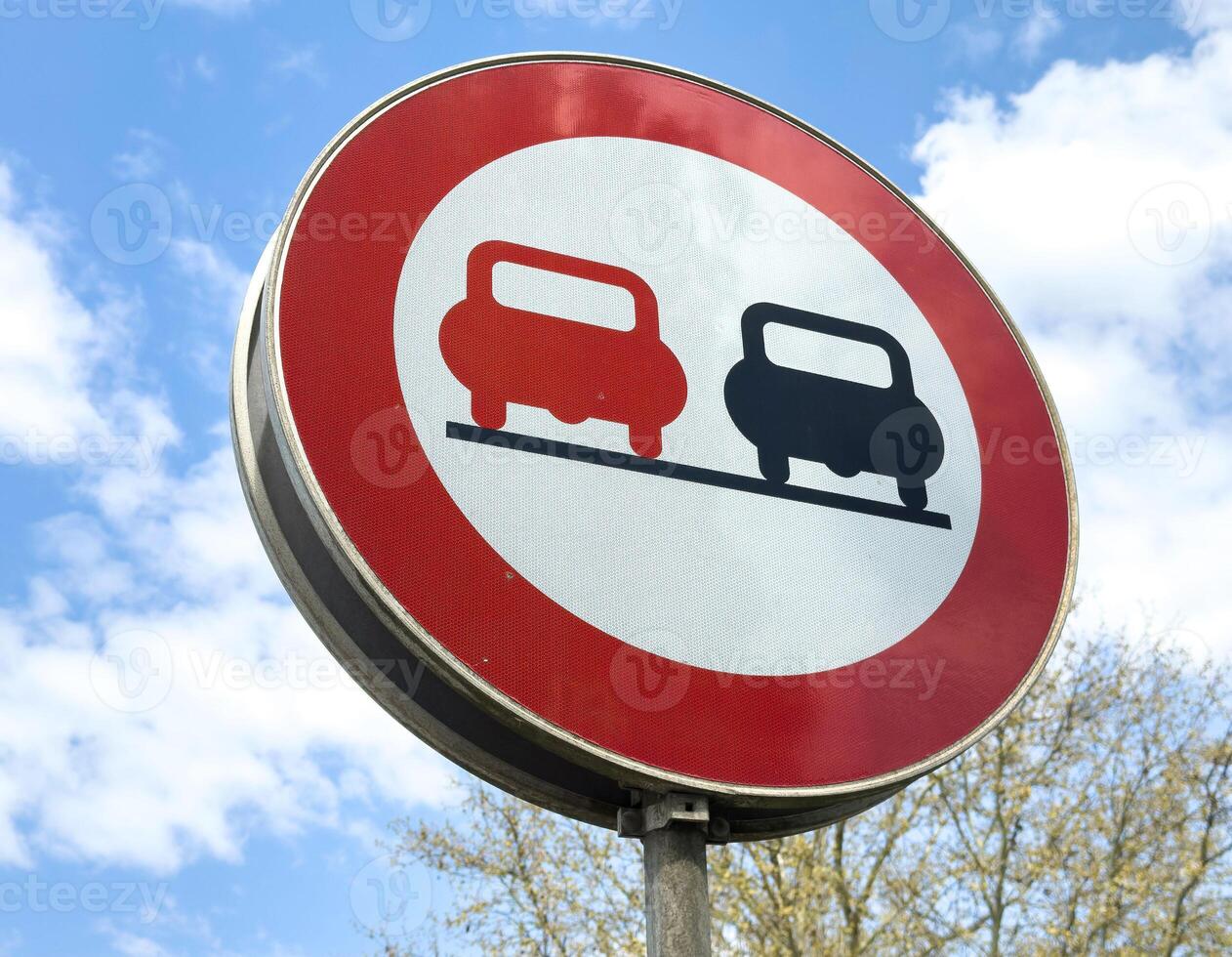 No overtaking road sign against blue sky with clouds photo