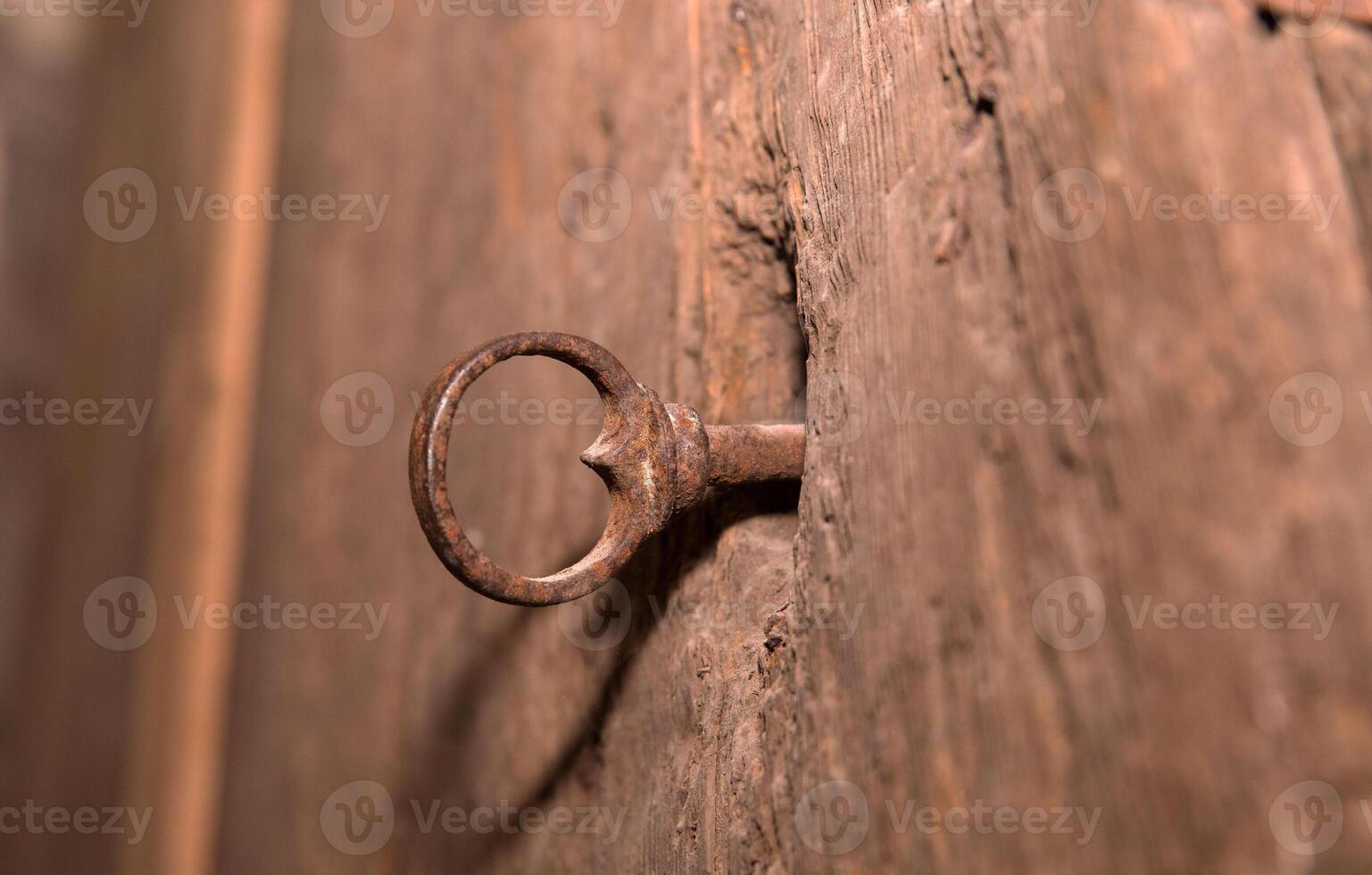 Rusty iron key in weathered wooden door lock with vintage texture photo