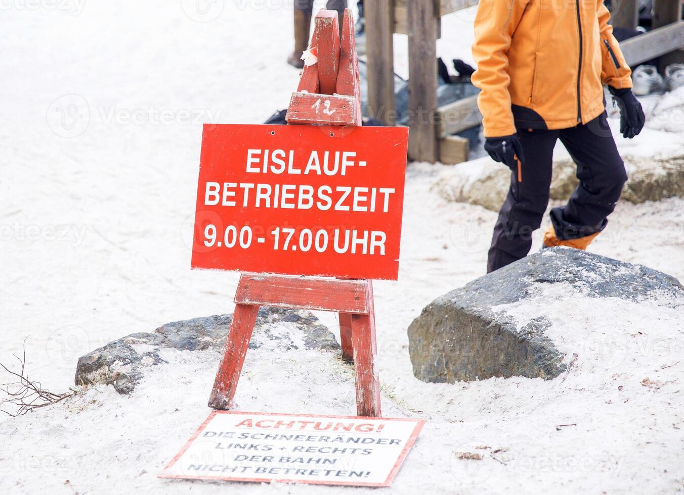 German ice skating area sign with schedule and safety warnings in winter setting photo