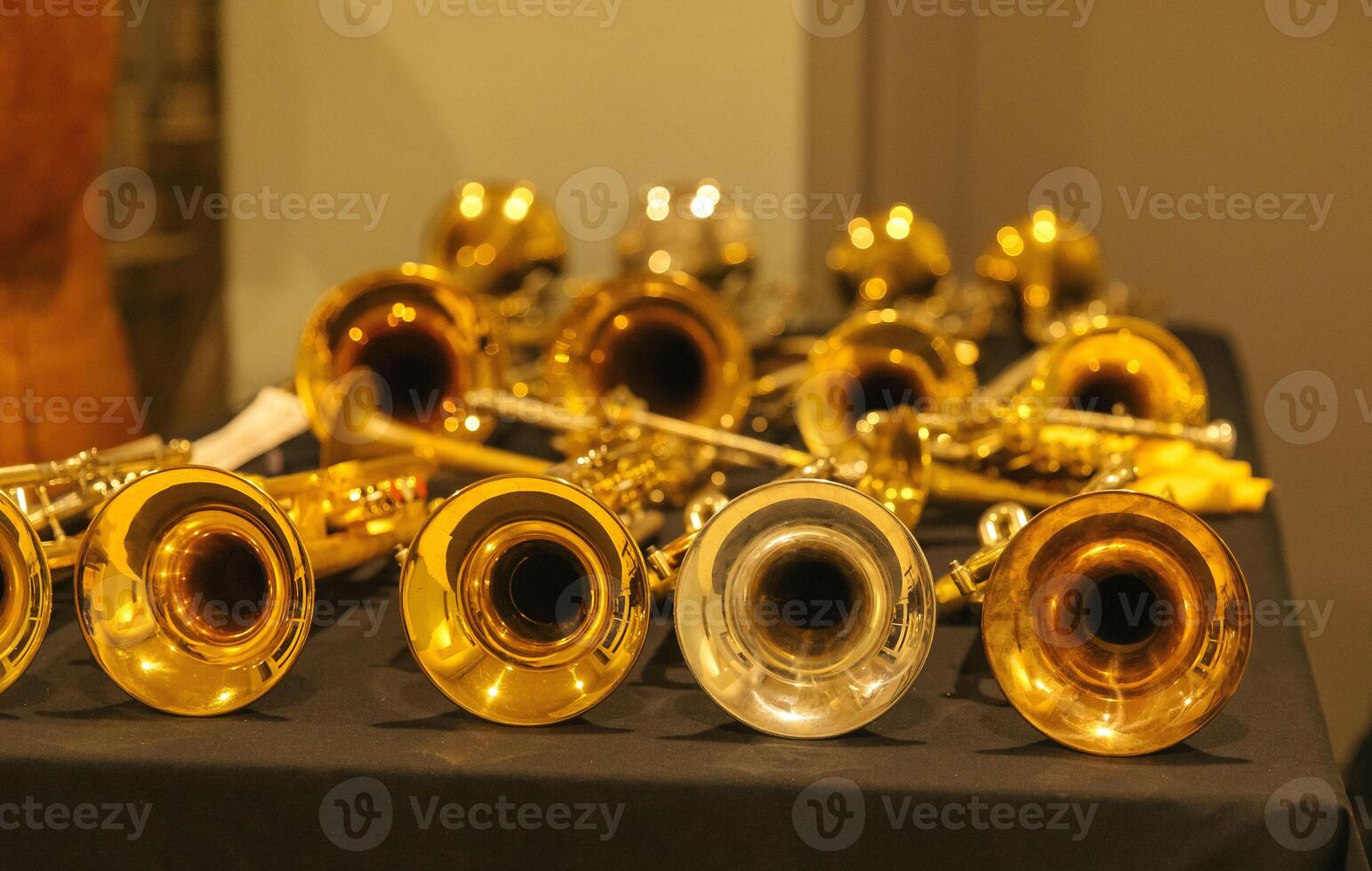 Array of brass and silver trumpets on black table display photo
