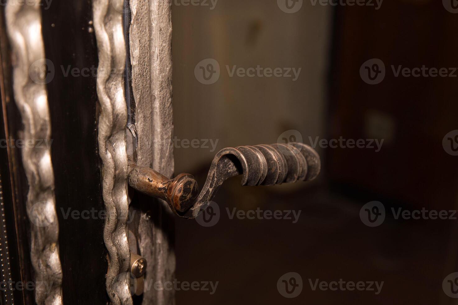 Vintage door handle close-up on textured metallic surface in dim light photo