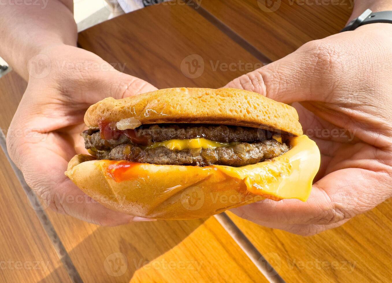 Delicious double cheeseburger with ketchup and cheese in hands photo