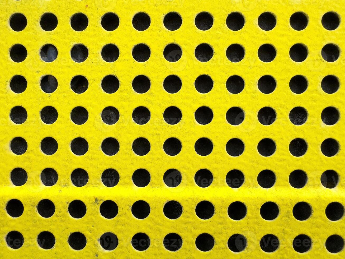 Yellow perforated surface with uniform circular patterns for industrial design photo