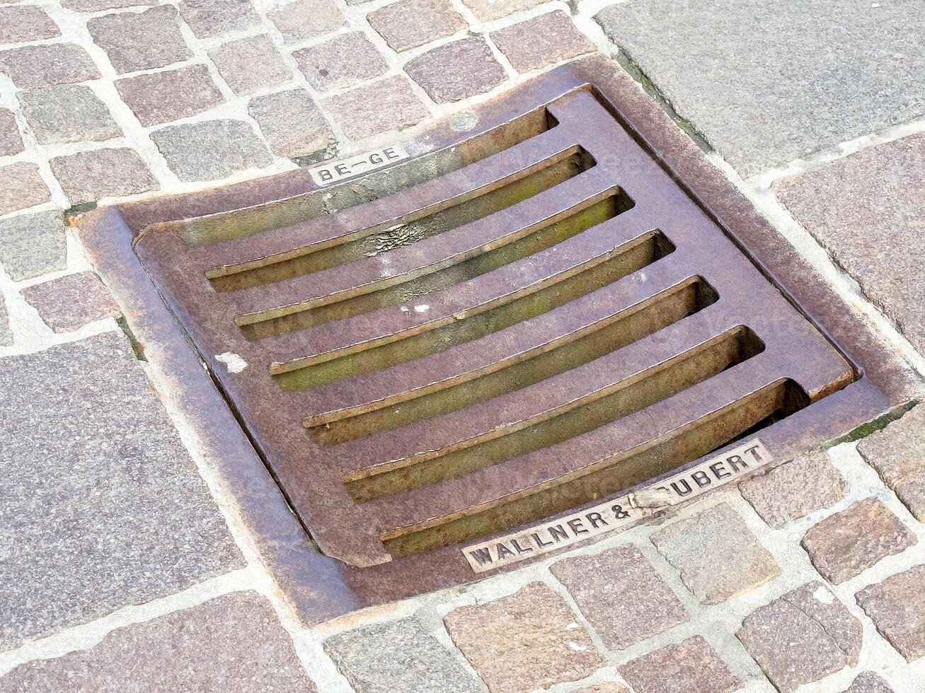 Street cobbled stone drainage grate on urban pavement photo