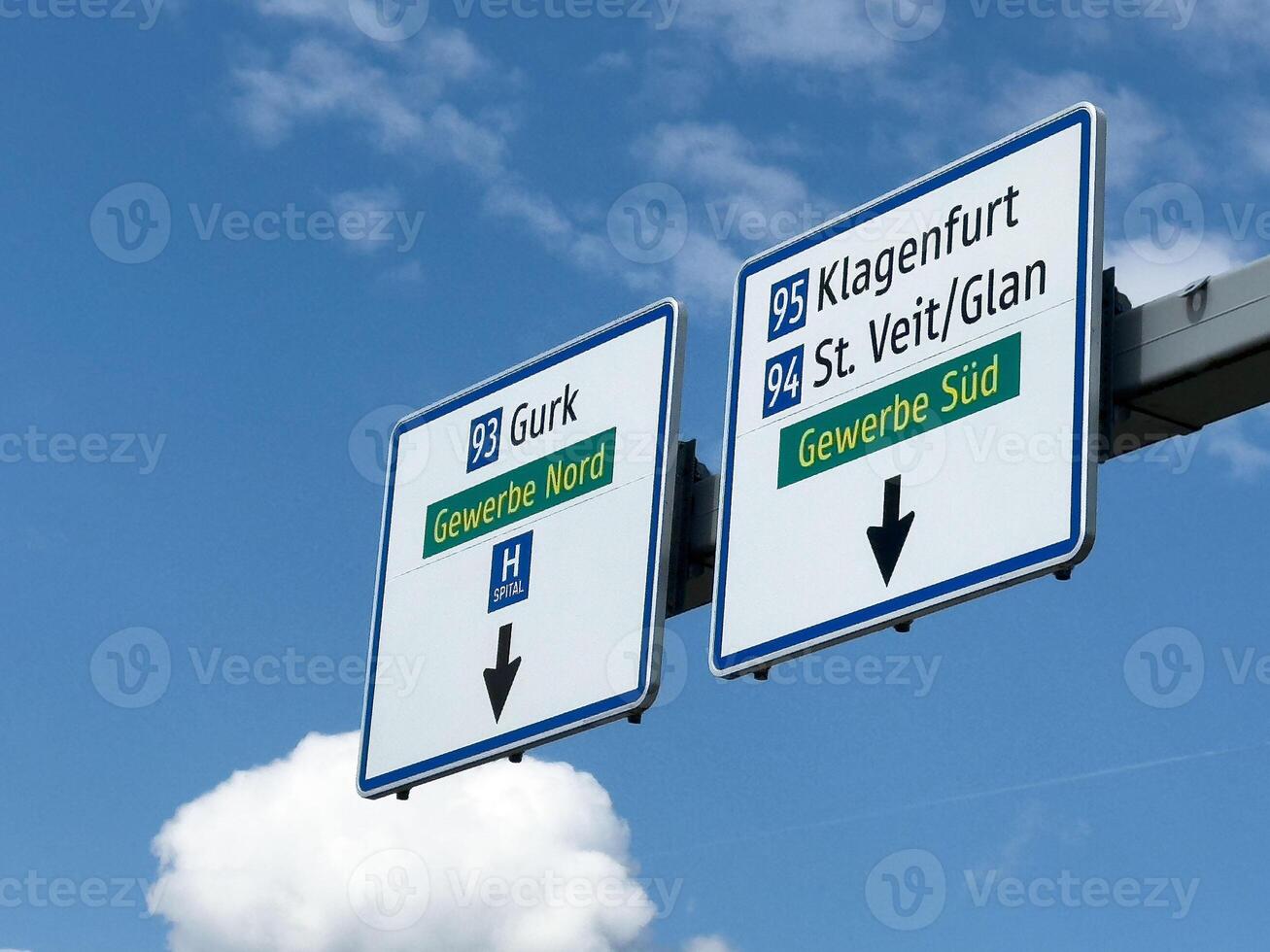 Austrian highway signs for klagenfurt and st. veit glan under blue sky with clouds photo