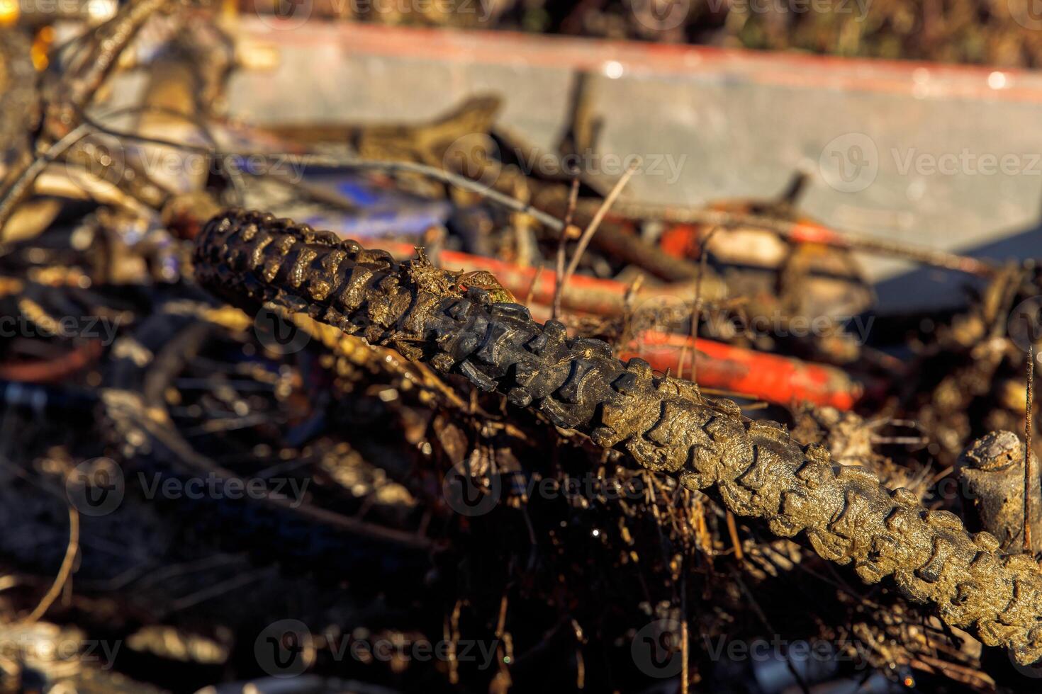 Mud-covered bicycle tires on abandoned mountain bike outdoors photo