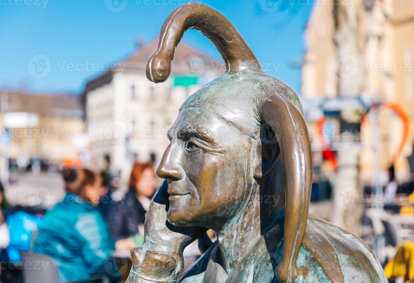 Bronze statue of jester in european city plaza on a sunny day photo