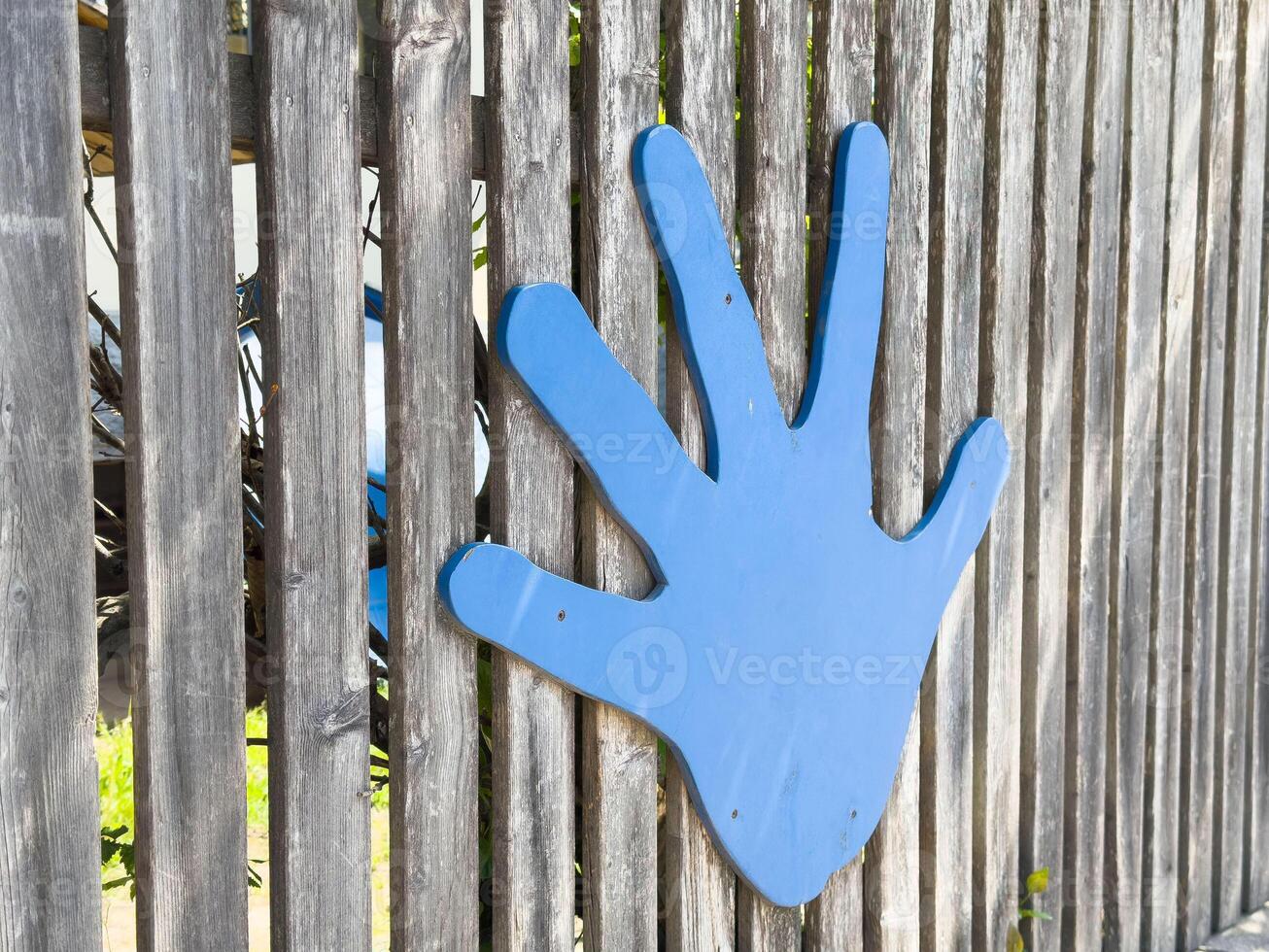 Blue hand cutout on wooden fence in outdoor play area photo