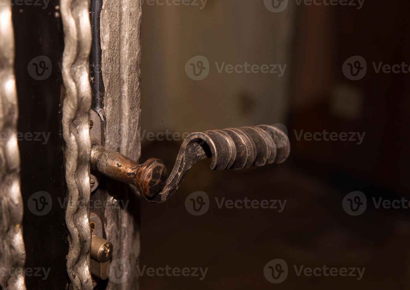 Close-up of a rustic metal door handle with intricate design and patina texture photo