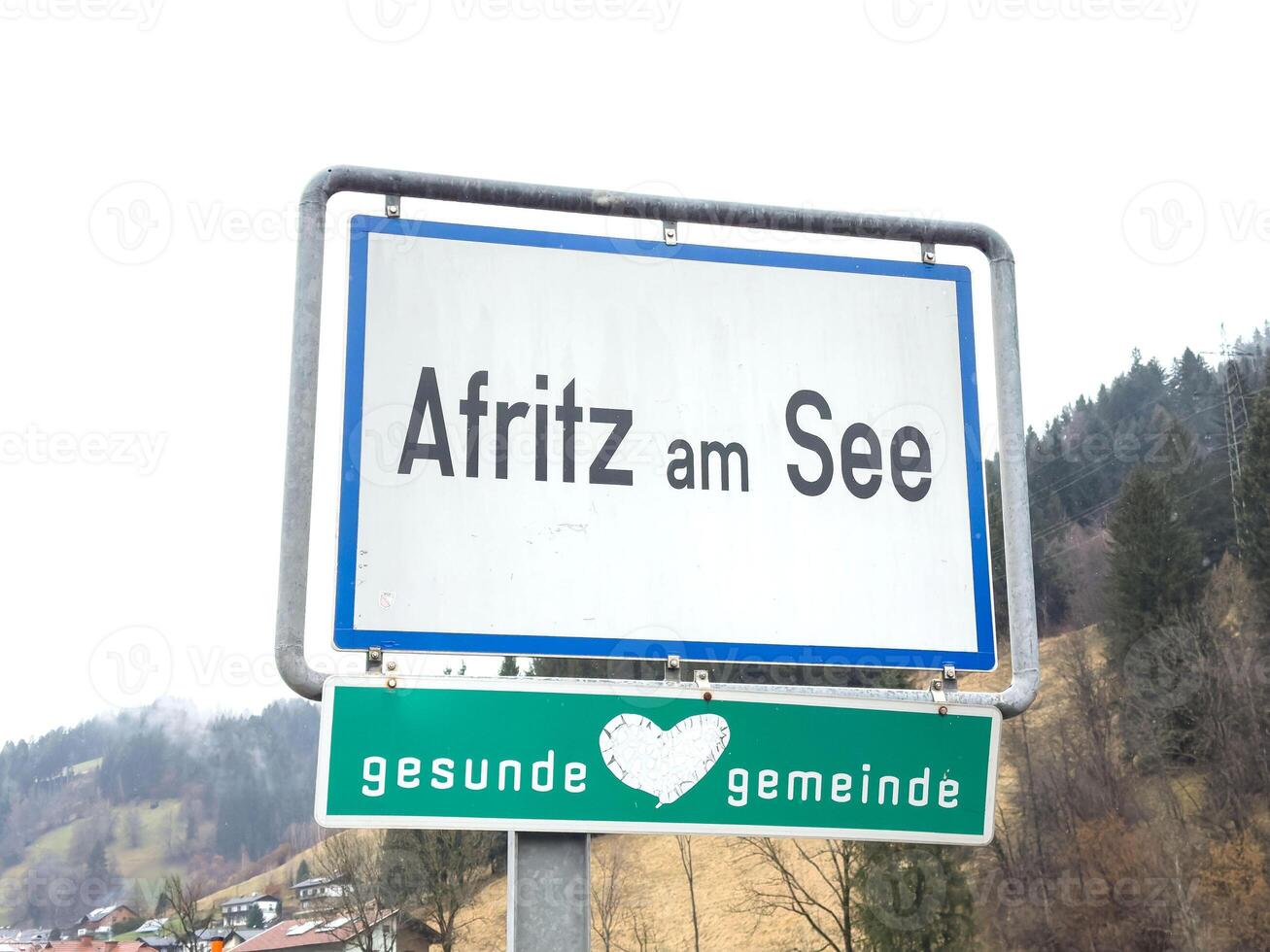 Afritz am see town sign in scenic winter landscape with snowy mountains and trees photo