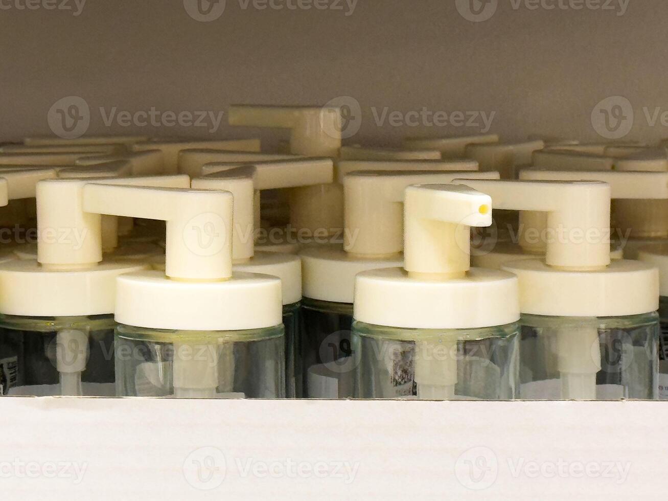 Organized row of white soap dispensers with pump nozzles in retail shelf display photo