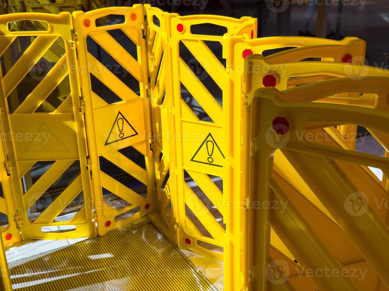Yellow caution barrier with warning symbols in public area photo