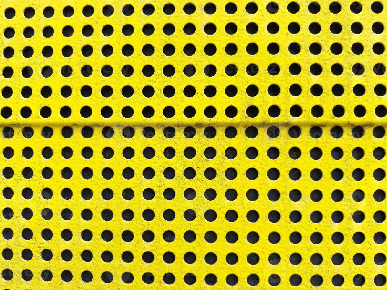 Yellow perforated metal surface with uniform circular holes pattern photo