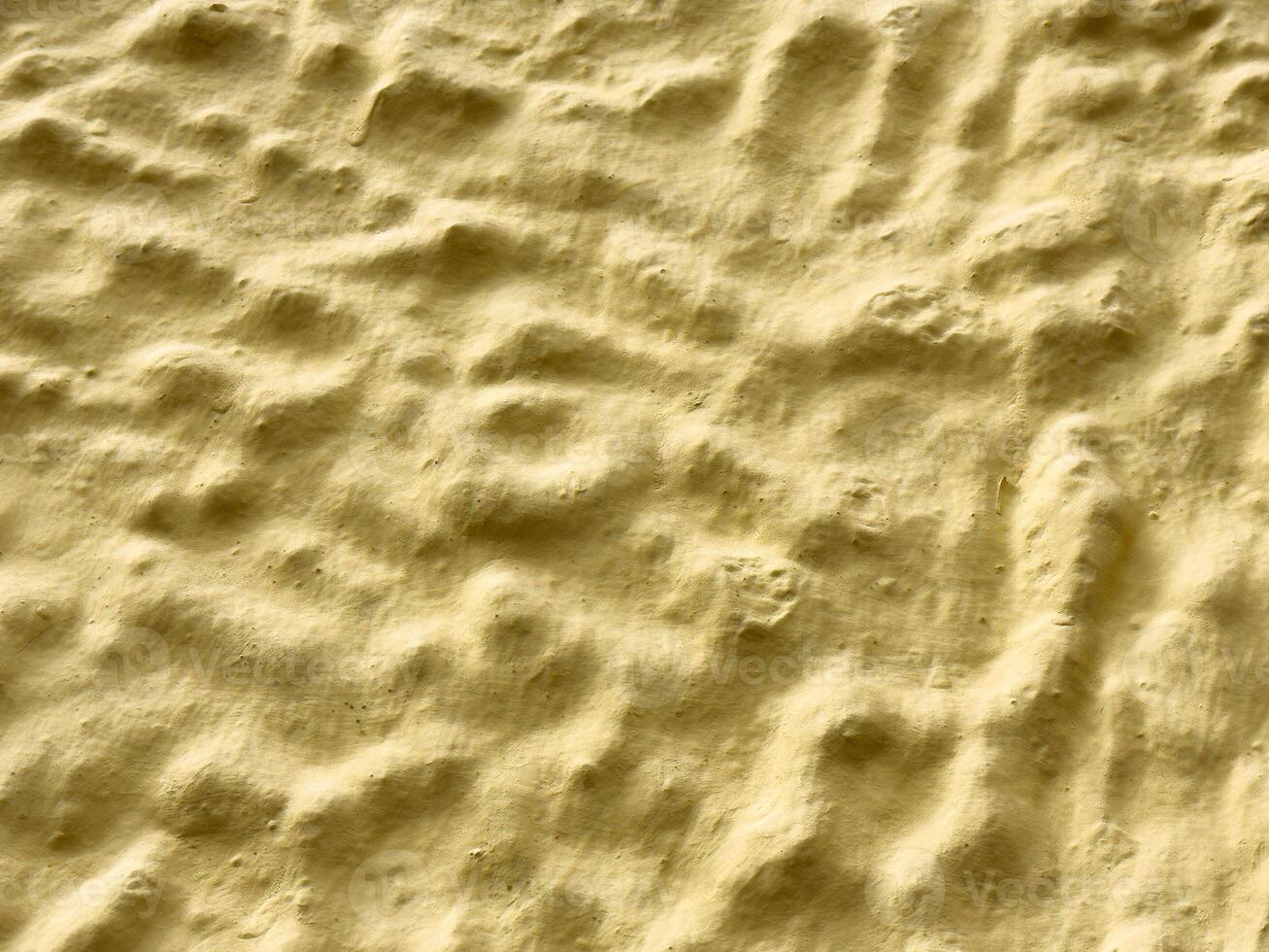Textured yellow surface with wavy patterns and shadows photo