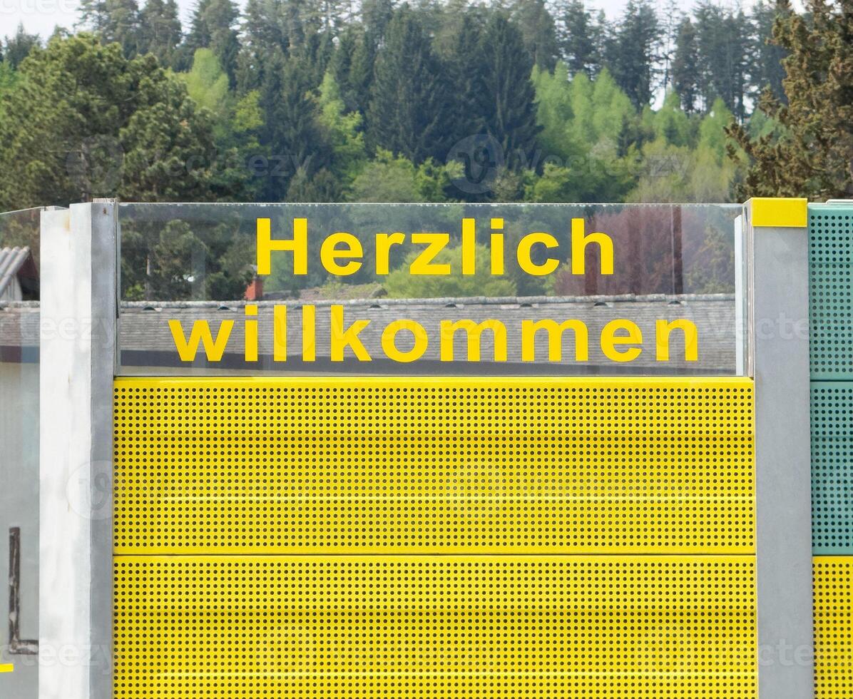Herzlich willkommen sign on yellow wall with forest background photo