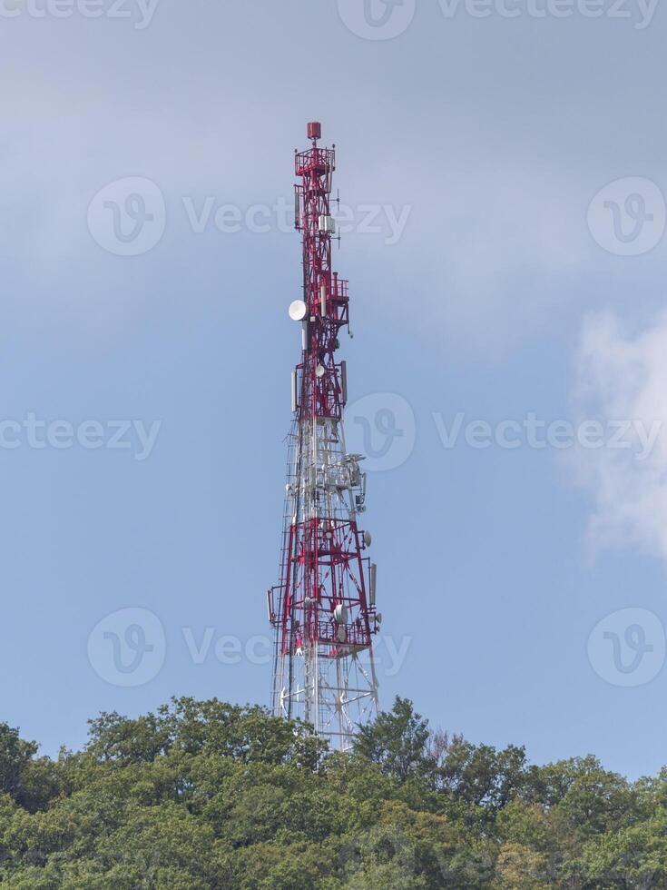 Directional antenna array on a red and white communication tower against sky. photo