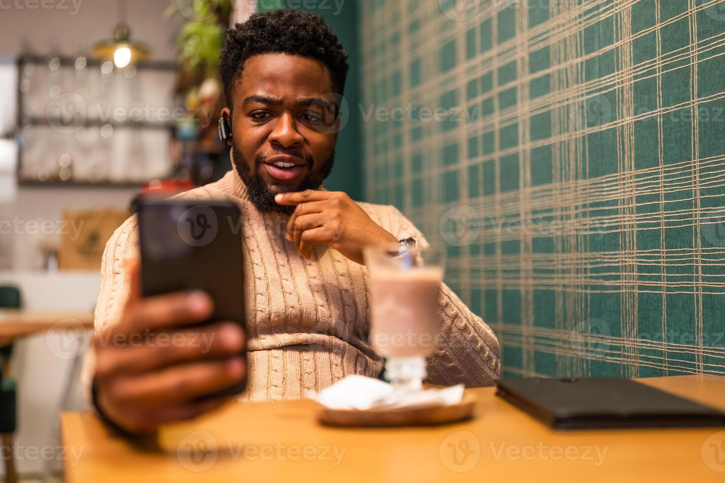 Frustrated African American male looking annoyed and angry while explaining something during phone discussion at the bar. photo