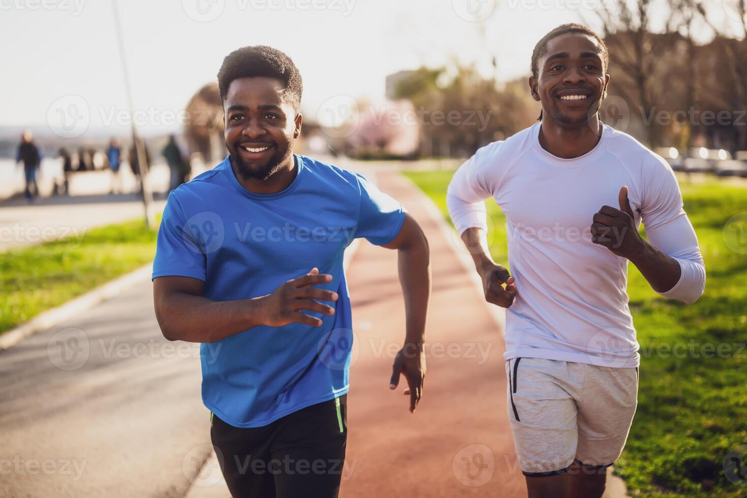 Energetic young African friends enjoying jogging together on a running track, showcasing teamwork and vitality while working out on a beautiful day. photo