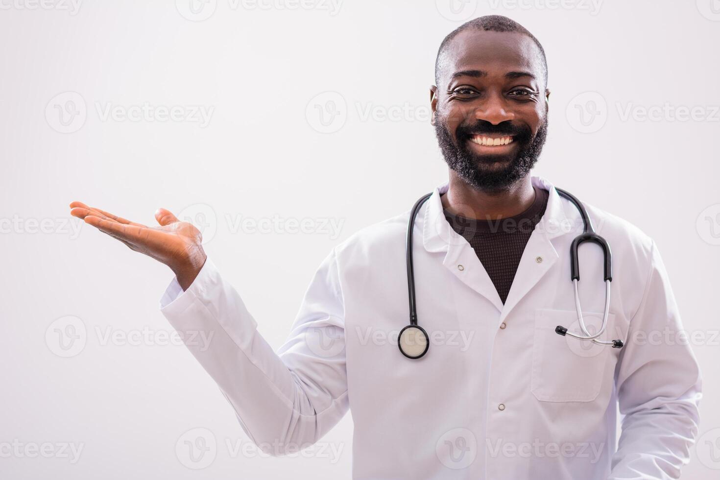 Portrait of smiling African American doctor who is holding blank space for your advert on gray background. photo